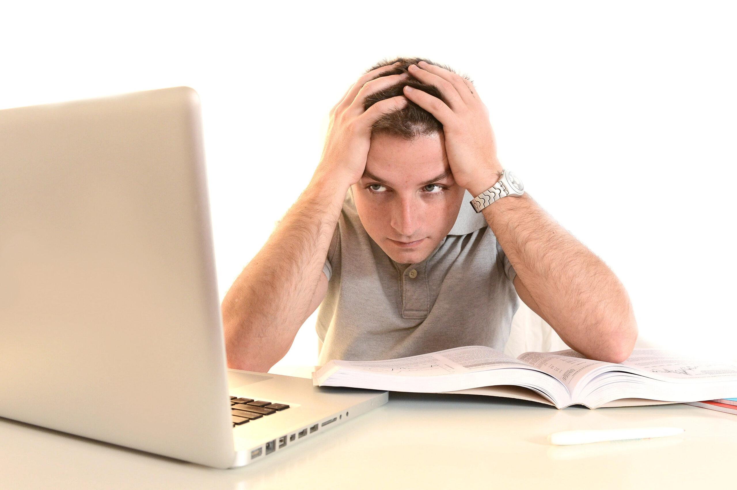 Mann sitzt mit frustriertem Gesichtsausdruck vor Laptop und Unterlagen, hält den Kopf in den Händen – Symbolbild für Erschöpfung und Motivationsverlust.
