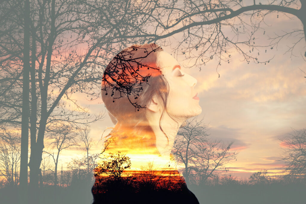 Doppelbelichtung: Profil einer Frau mit geschlossenen Augen vor einem Sonnenuntergang, kombiniert mit Silhouetten von Bäumen – Symbol für Intuition und innere Verbundenheit.